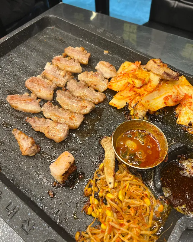 불판 위에 구워진 흑돼지 오겹살과 김치