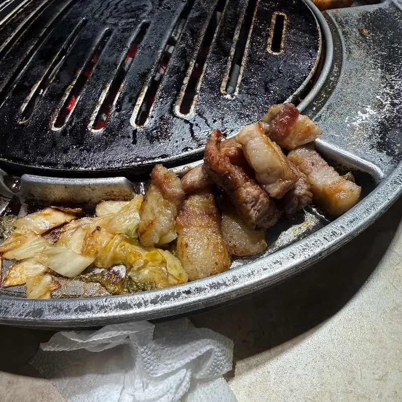 잘 익은 고기를 젓가락으로 집어 올리는 모습