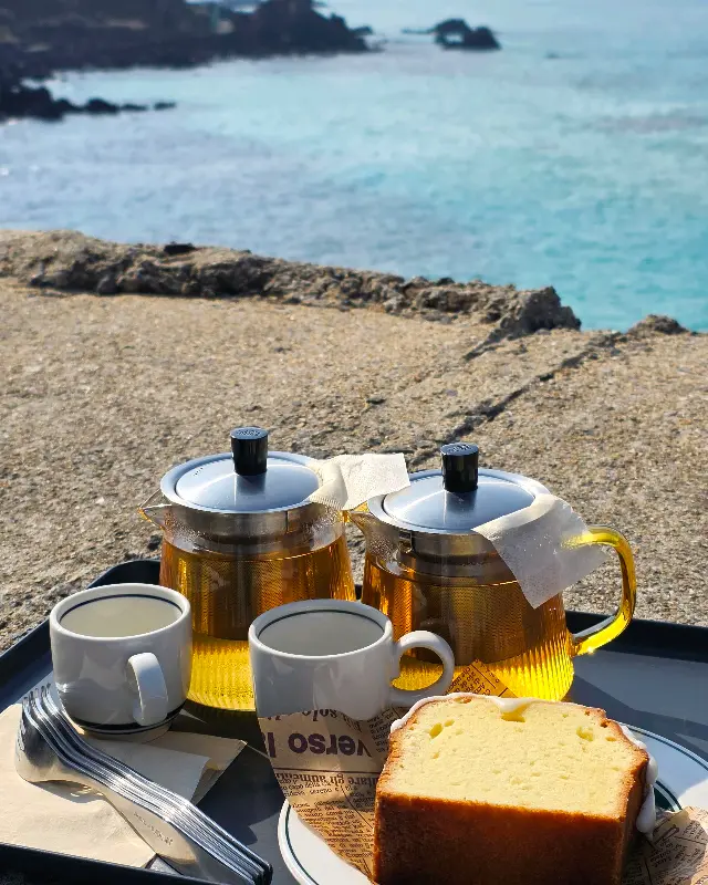 바다를 배경으로 놓인 티팟 세트와 파운드 케이크