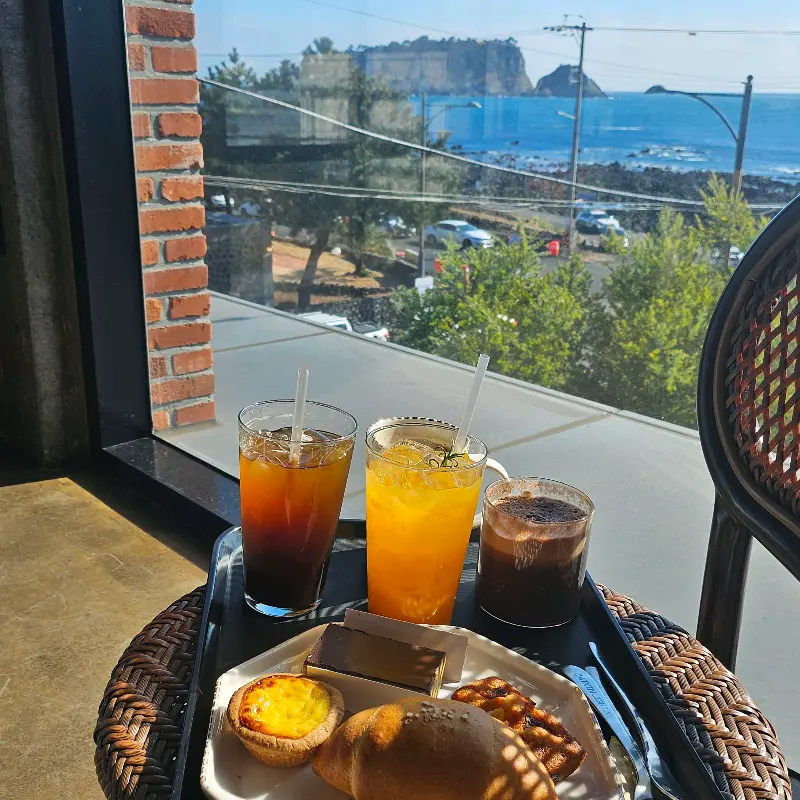 테이블 위에 놓인 음료와 디저트, 창밖으로 보이는 범섬