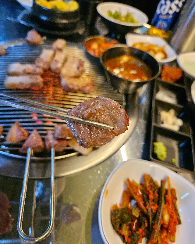 잘 구워진 흑돼지 한 점을 젓가락으로 집어 올린 모습