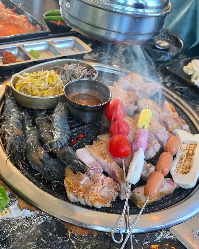 숯불 위에서 맛있게 익어가는 흑돼지 오겹살과 새우, 버섯