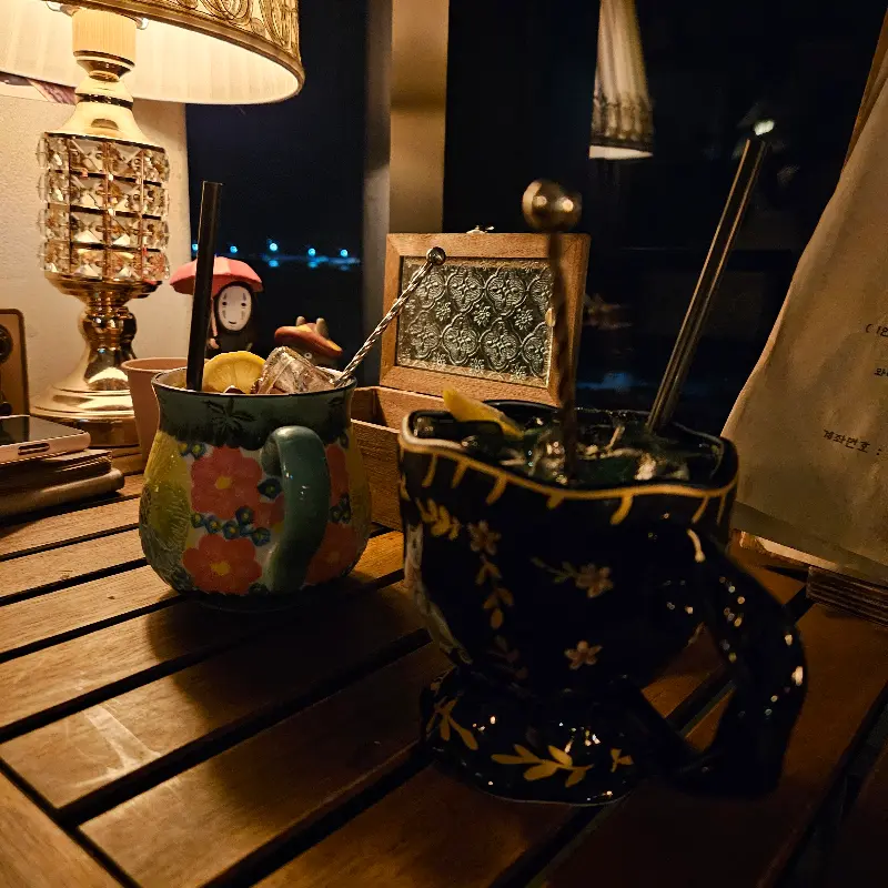 앤틱한 테이블 위에 놓인, 꽃무늬 머그컵에 담긴 칵테일 두 잔