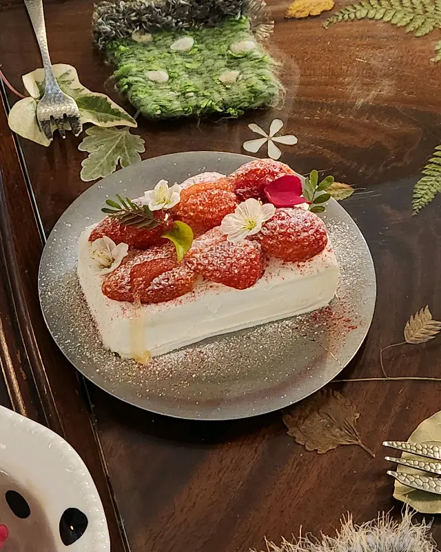 딸기 티라미수 클로즈업 샷: 딸기와 꽃으로 화려하게 장식되어 있다.