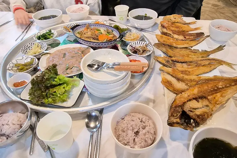 제주할망밥상의 푸짐한 한 상 차림 사진. 다양한 생선구이와 반찬들이 은쟁반 위에 가득 담겨 있다.