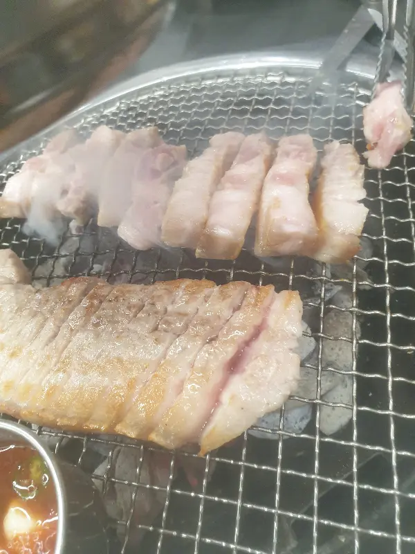 숯불 위에서 노릇하게 구워지는 흑돼지 오겹살