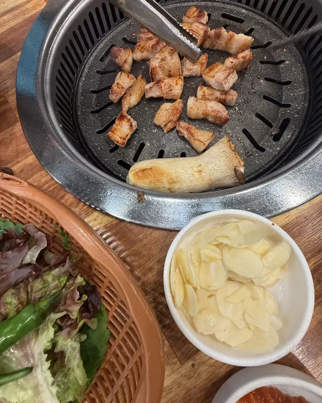 불판 위에 익어가는 흑돼지 오겹살과 버섯