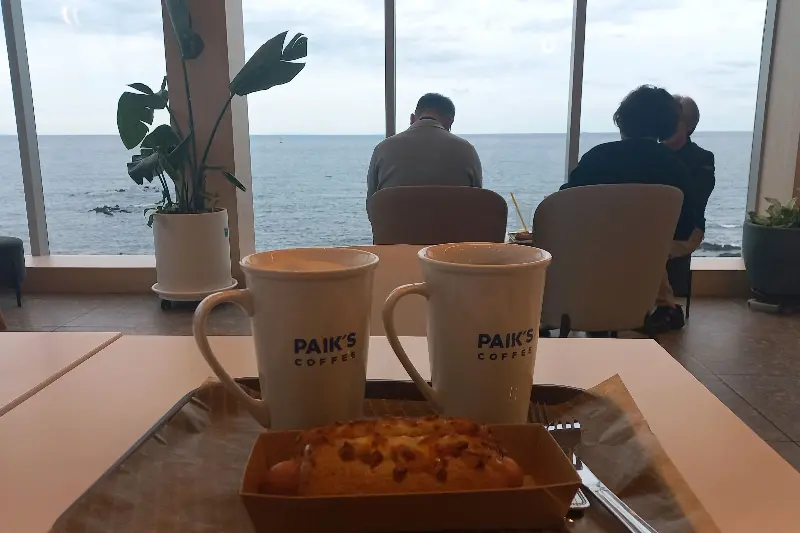 커피와 빵이 놓인 테이블과 창밖 풍경