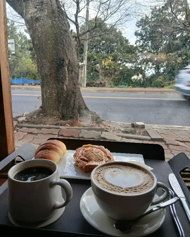 창밖 풍경을 바라보며 커피를 즐기는 모습