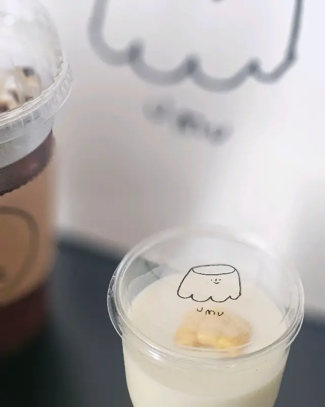 투명한 컵에 담긴 커스터드 푸딩 위에 우무 캐릭터 스티커가 붙어있는 모습
