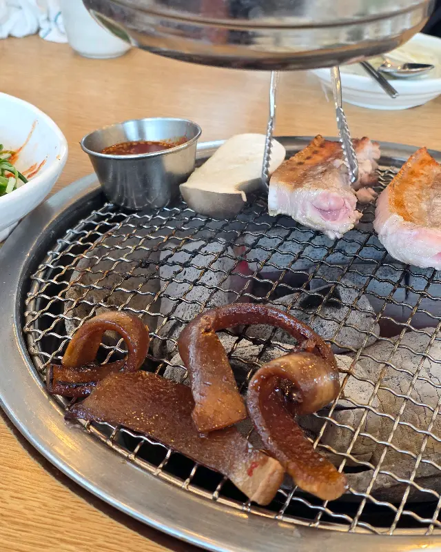 숯불 위에 구워지는 흑돼지 오겹살과 껍데기