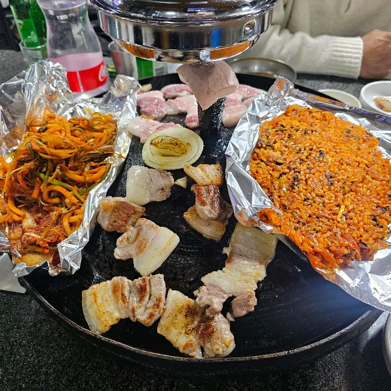 솥뚜껑 위에 구워지는 오겹살과 김치, 파채, 볶음밥
