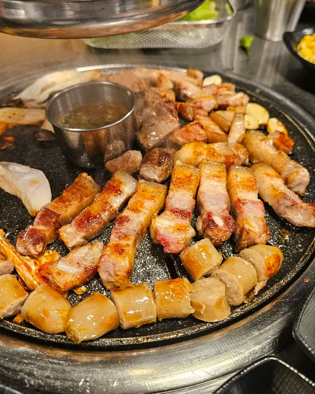 불판 가득 구워진 흑돼지, 소시지, 버섯