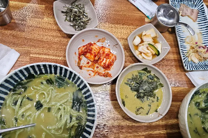 테이블 위에 놓인 보말칼국수, 보말국, 김치, 깍두기 등의 모습
