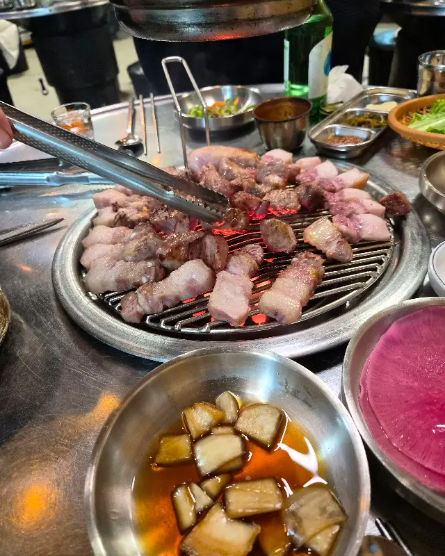 연탄불 위에서 노릇하게 익어가는 흑돼지 오겹살