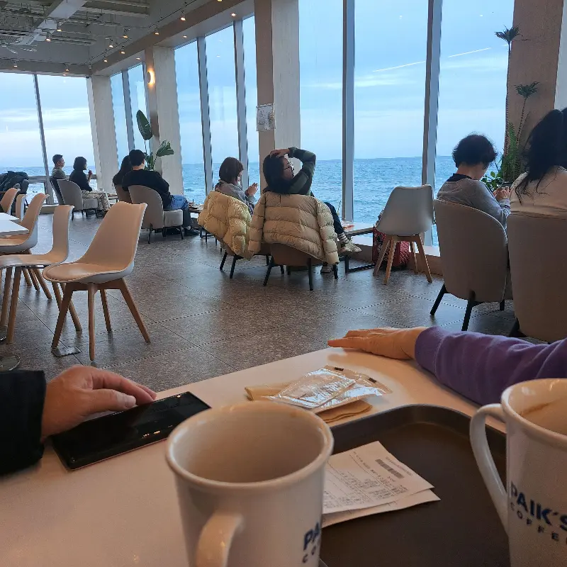 통창으로 제주 바다를 감상하는 사람들