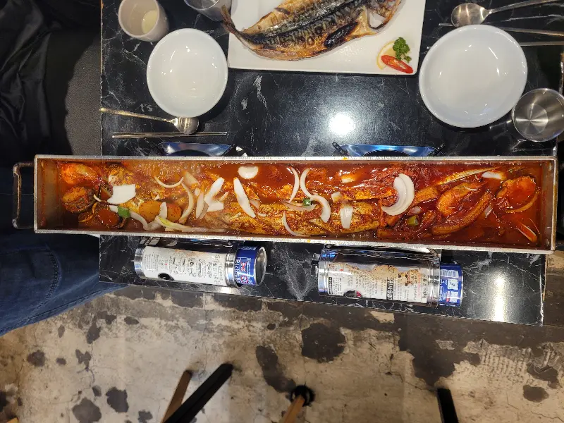 테이블 위에서 끓고 있는 갈치조림과 구워진 고등어