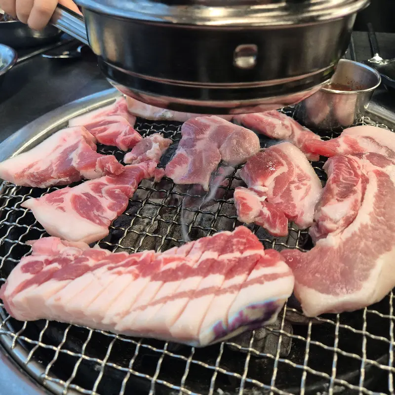 불판 위에서 익어가는 제주 흑돼지 오겹살의 모습