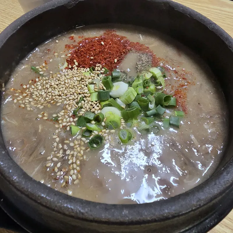 고춧가루, 파, 깨가 뿌려진 고사리 해장국의 클로즈업 샷