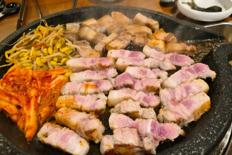 돌판 위에 가득 찬 흑돼지 오겹살과 밑반찬