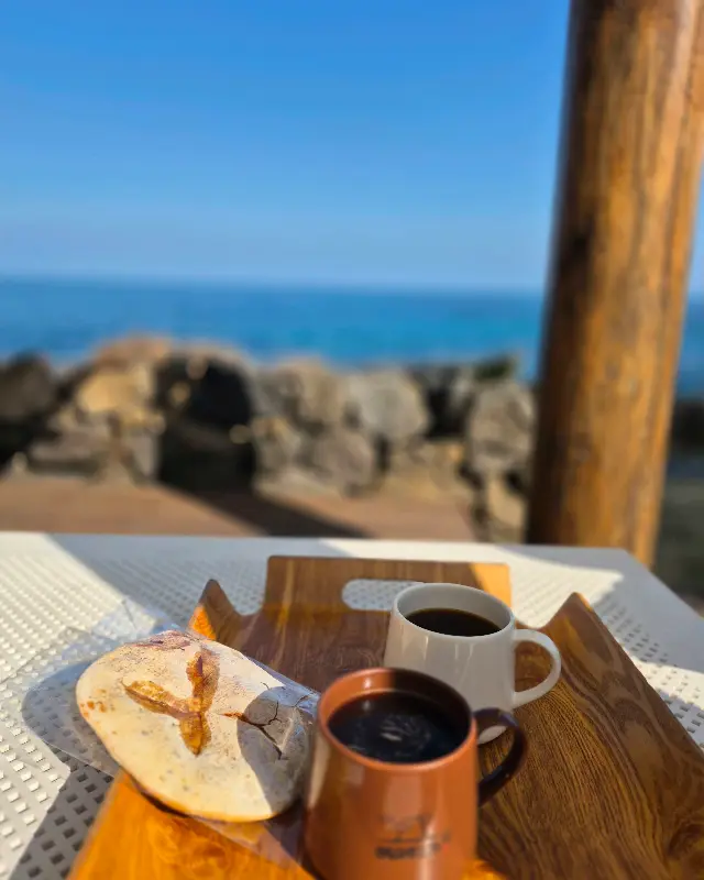 바다를 배경으로 놓인 빵과 커피 사진