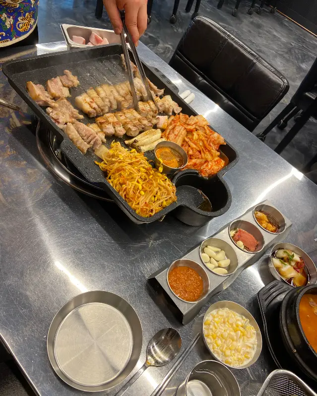 직원분이 능숙한 솜씨로 흑돼지 오겹살을 굽고 있는 모습