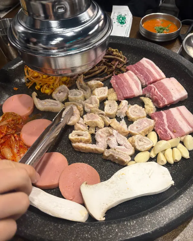 막창과 삼겹살, 콩나물, 김치, 버섯 등이 불판 위에 올려져 있는 모습