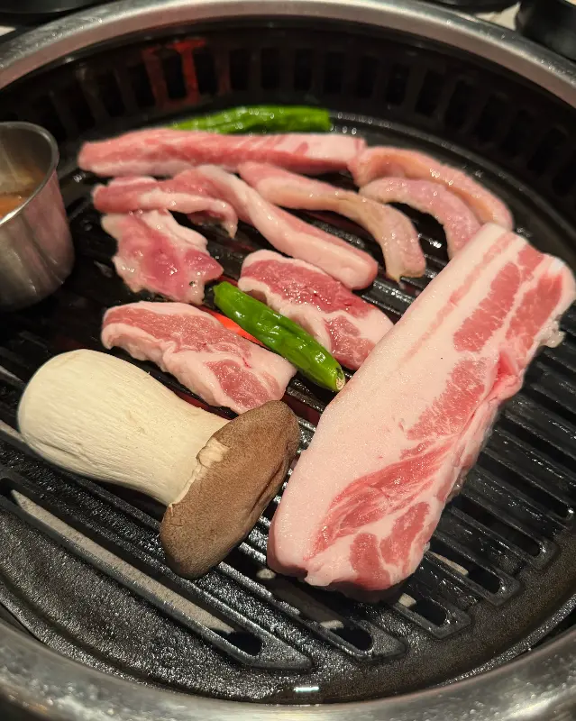 돈가도의 숯불 위에 올려진 흑돼지 오겹살과 팽이버섯, 멜젓