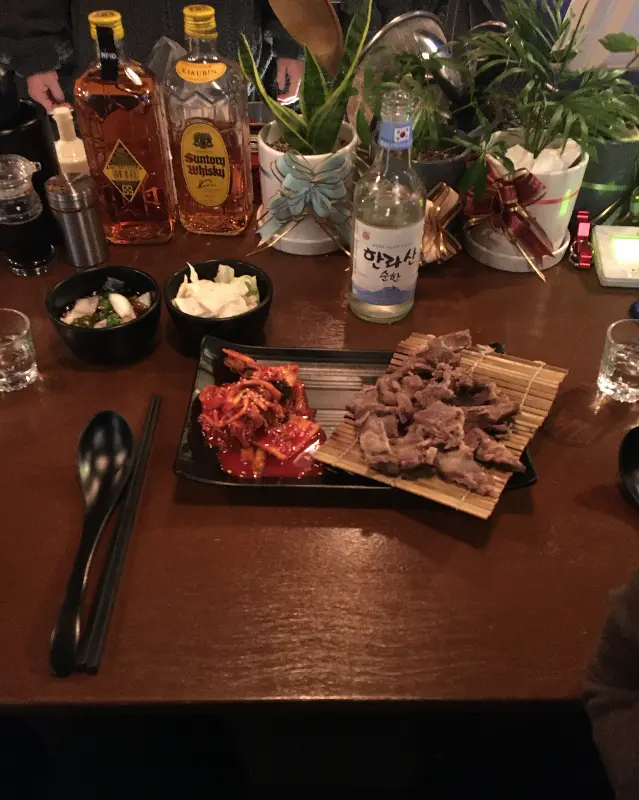 테이블 위에 놓인 스지 수육과 김치, 술병