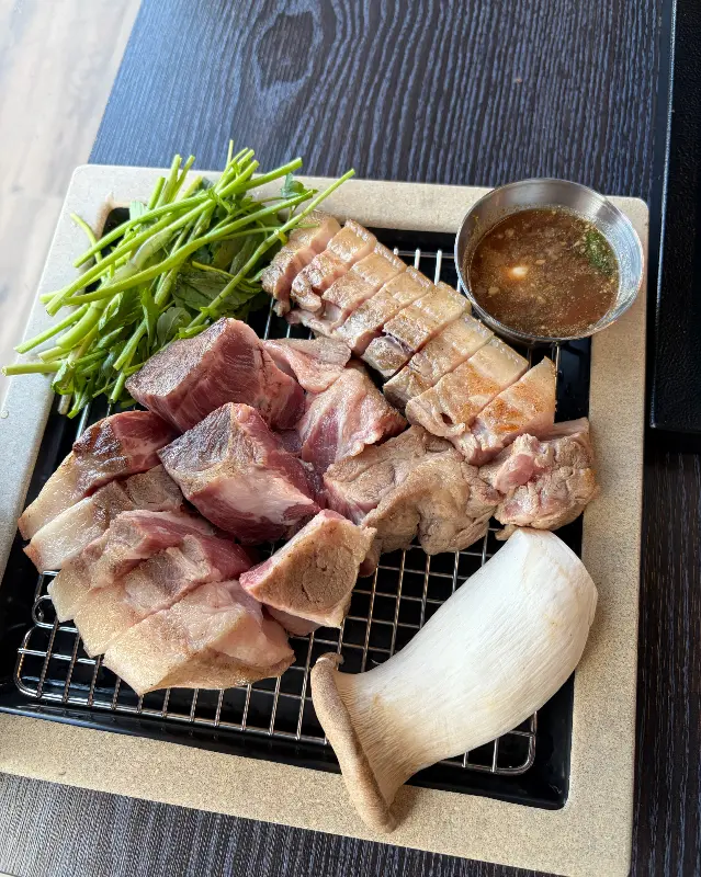 잘 익은 흑돼지를 쌈 채소에 싸서 한 입 가득