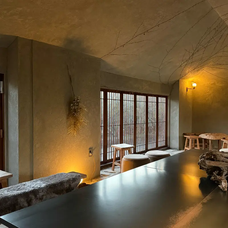 카페 내부, 나무 테이블과 의자가 놓여 있고, 은은한 조명이 공간을 밝히고 있다.