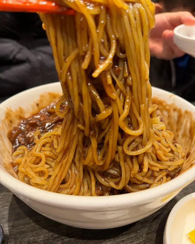 젓가락으로 짜장면 면발을 들어올리는 모습