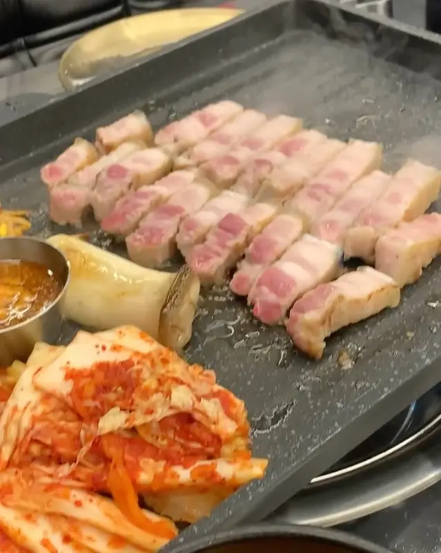 잘 익은 흑돼지 오겹살이 먹기 좋게 잘려져 불판 위에 놓여있는 모습