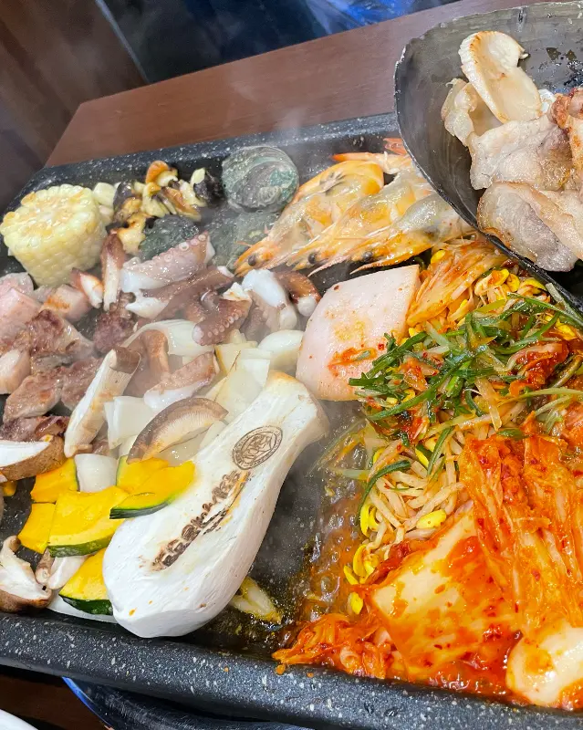 돌판 위에 푸짐하게 구워진 흑돼지해물삼합