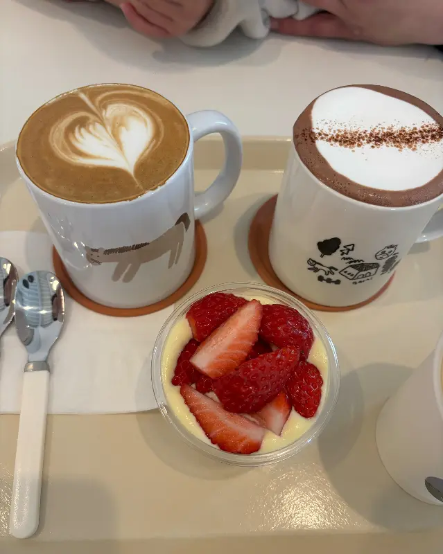 라떼 아트가 예쁜 라떼와 딸기가 올려진 푸딩이 쟁반 위에 놓여 있다.