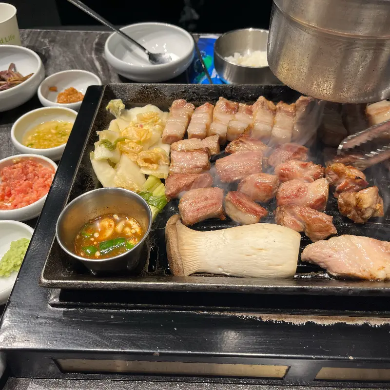 불판 가득 채워진 흑돼지와 버섯