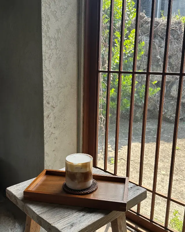 창가에 놓인 커피, 햇살이 은은하게 비추고 있다.