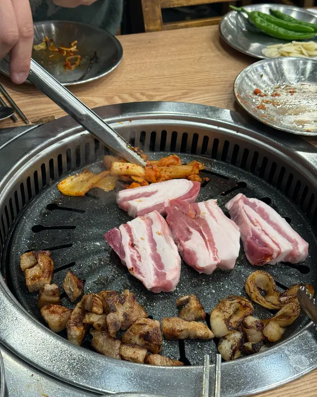 불판 위에서 익어가는 흑돼지 오겹살과 김치