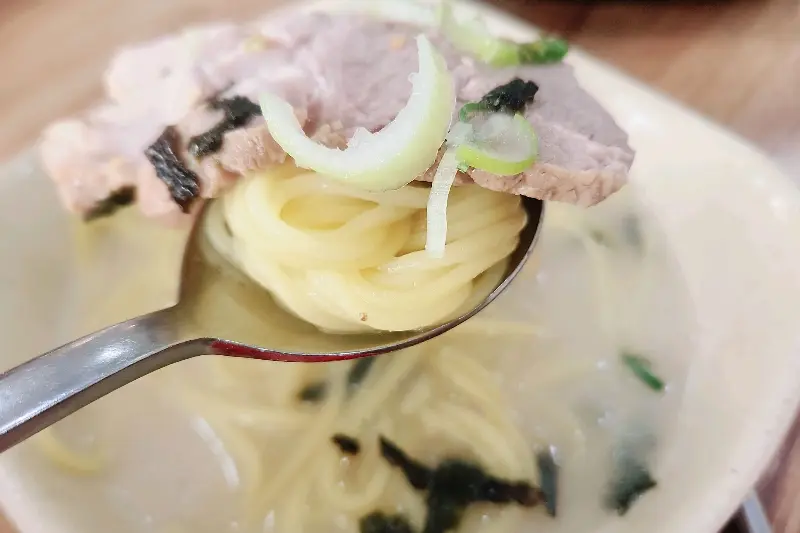 숟가락 위에 면과 고기를 함께 올려놓은 모습