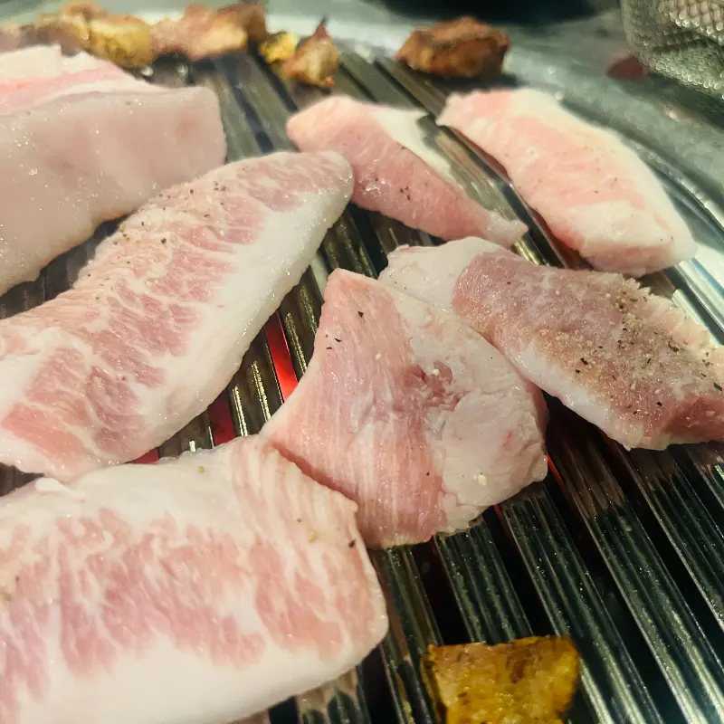 두툼한 흑돼지 근고기가 불판 위에서 지글거리는 모습