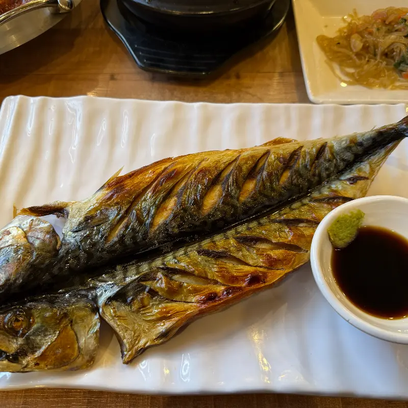 노릇하게 구워진 고등어 구이 클로즈업 샷. 윤기가 흐르는 껍질이 먹음직스럽다.