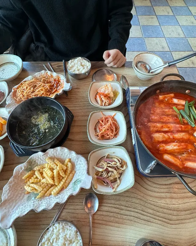 테이블 위에 놓인 갈치조림, 미역국, 스파게티, 감자튀김 등 다양한 음식들