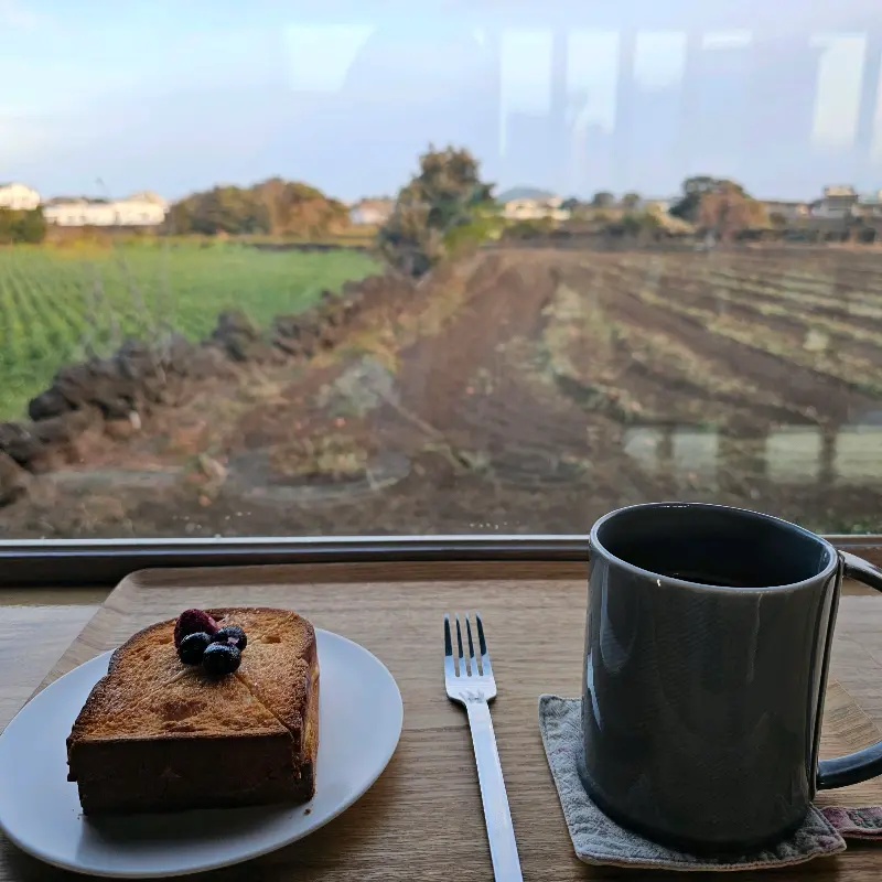 창밖 풍경을 바라보며 빵과 커피를 즐기는 모습