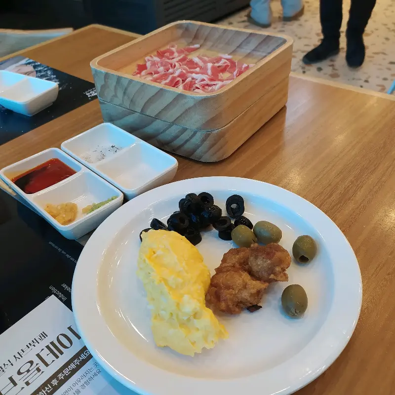 테이블 위에 놓인 샐러드바 음식 접시와 샤브샤브 재료