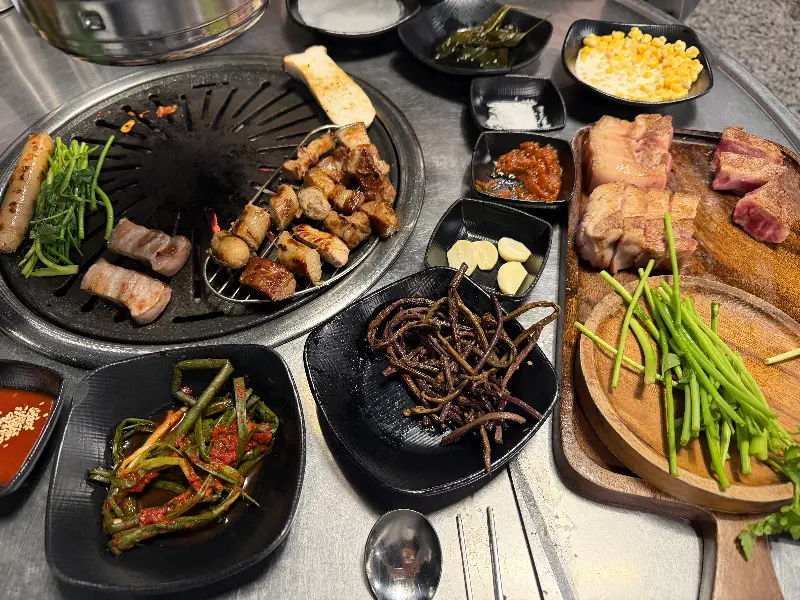 불판 위에 올려진 초벌 흑돼지, 김치, 멜젓