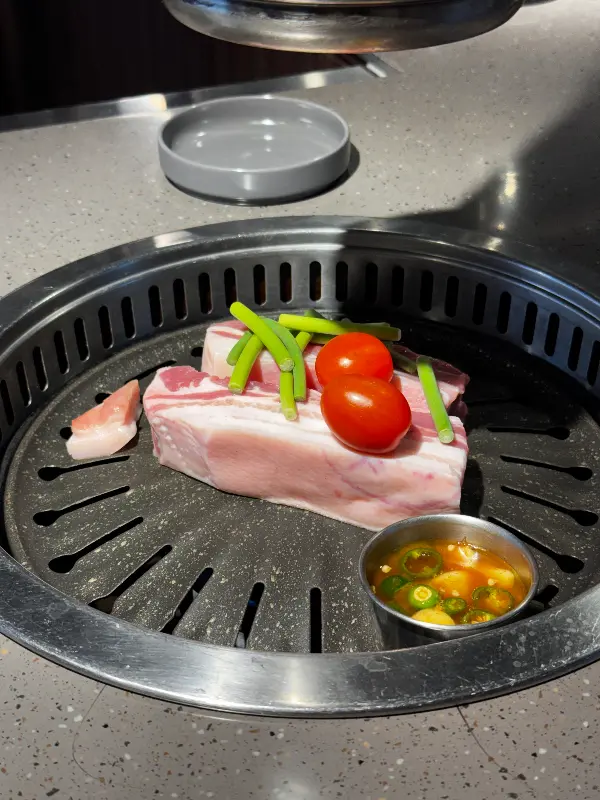 불판 위에 흑돼지 목살과 멜젓