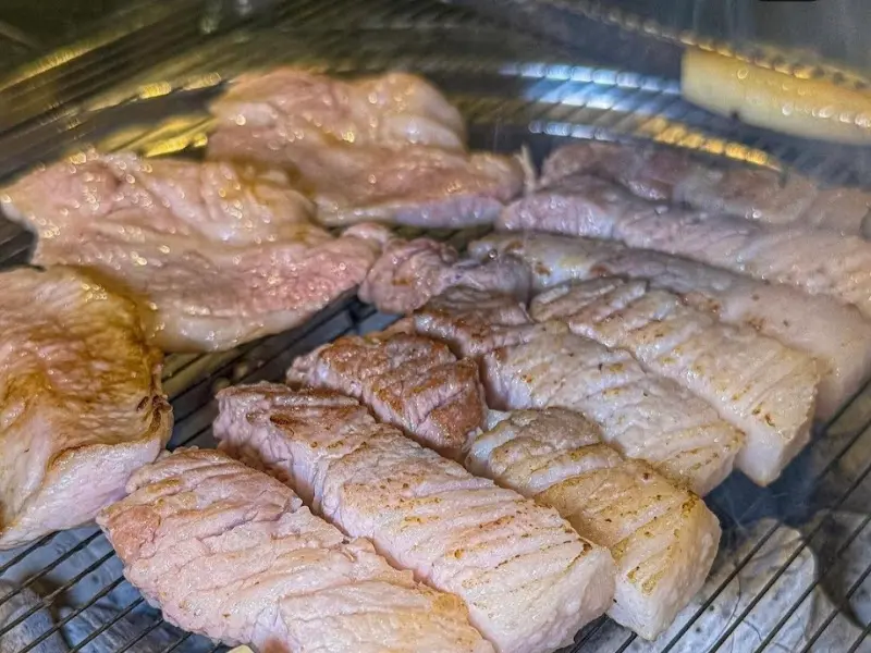 불판 가득 올려진 흑돼지 오겹살과 특수부위