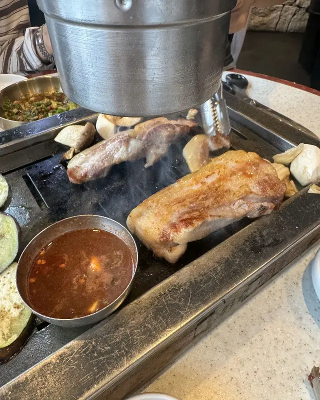 잘 구워진 흑돼지를 멜젓에 찍어먹는 모습