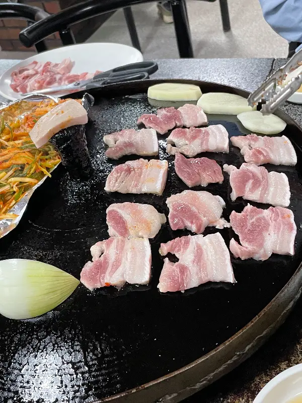 솥뚜껑 위에 구워지는 오겹살과 양파, 김치