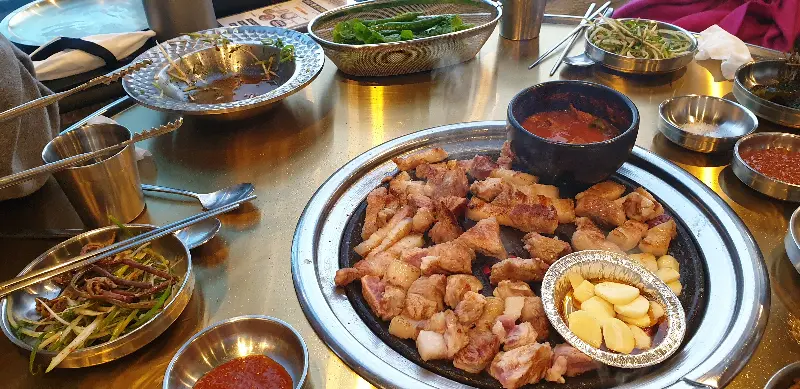 다 구워진 흑돼지를 멜젓에 찍어 먹는 모습